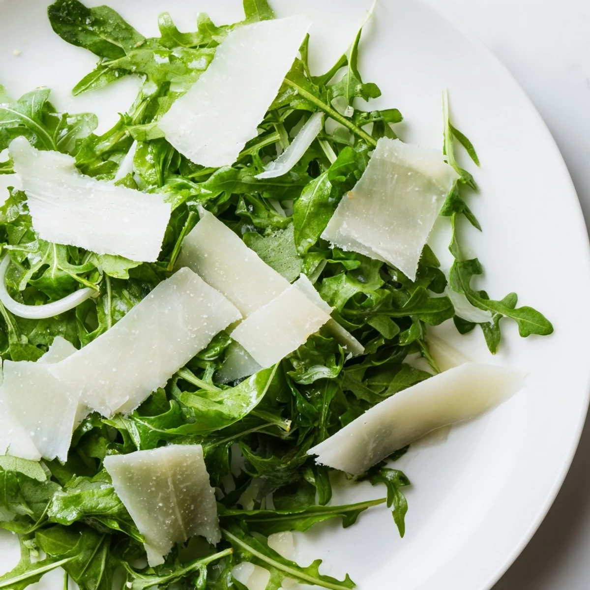 Fresh arugula salad with a tangy lemon dressing, Parmesan shavings, ready to serve and enjoy.