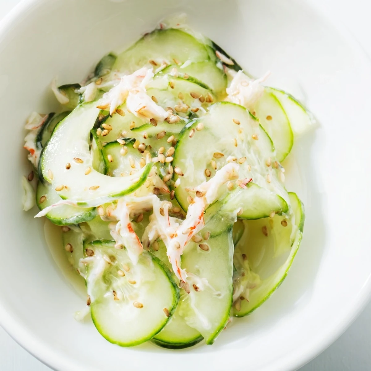 Bright California Roll Cucumber Salad with creamy dressing, crab, and sesame seeds, plated beside chopsticks for an easy, 15-minute appetizer.