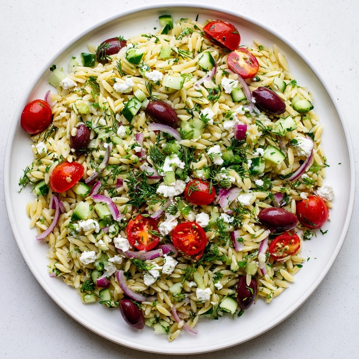 Freshly cooked orzo salad with diced cucumbers, cherry tomatoes, and crumbled feta, tossed in a bright lemon-oregano dressing.  