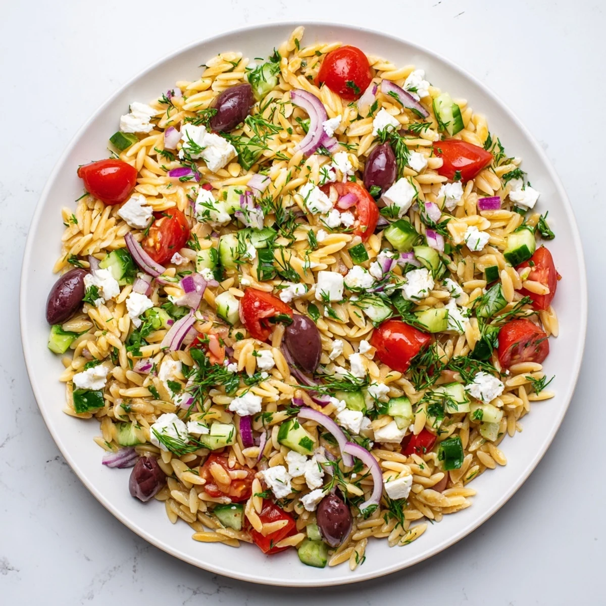 Bright Greek orzo salad with red onion, Kalamata olives, and herbs, served chilled on a rustic wooden board.  