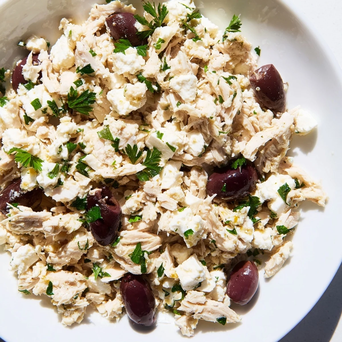 Colorful Mediterranean Chickpea Chicken Salad in a white bowl, drizzled with zesty dressing and garnished with red onion and feta.