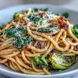 A skillet of Cabbage Pasta With Garlic and Parmesan beside crusty bread and a glass of white wine.