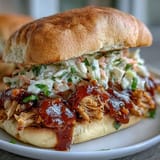 Slow-cooked tender chicken in smoky barbecue sauce, served hot with crunchy coleslaw on a toasted bun.  