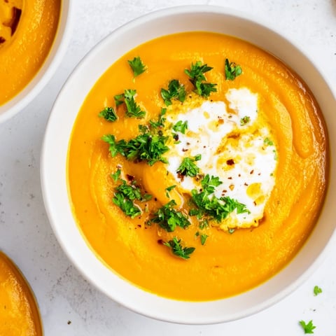 Steaming bowl of Sweet Maple Carrot Soup, garnished with parsley for a vibrant color contrast.
