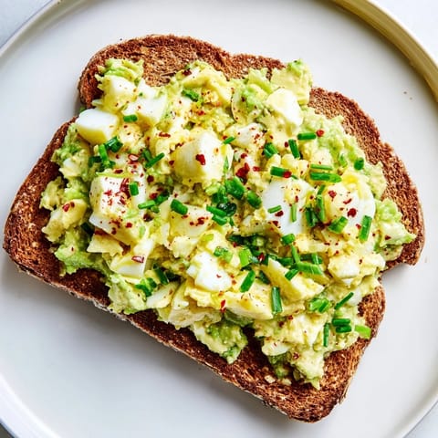 Freshly made avocado egg smash, featuring herbs, lemon, and perfectly mashed eggs for toast.