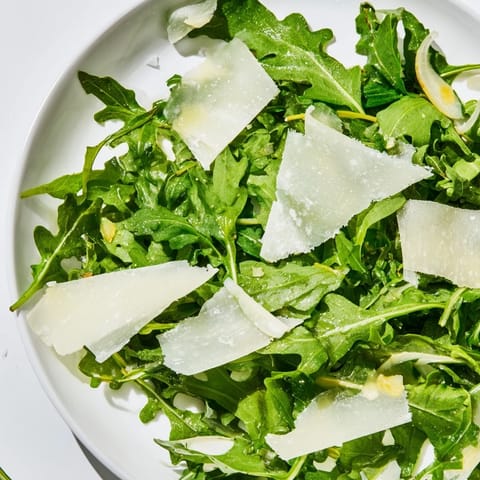 This vibrant arugula salad features peppery greens coated in zesty lemon dressing, ready to eat.
