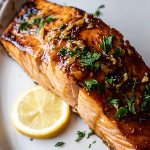 Bright lemon wedges and fresh parsley garnish these succulent honey garlic glazed salmon fillets, a quick, elegant main dish ready in 25 minutes.