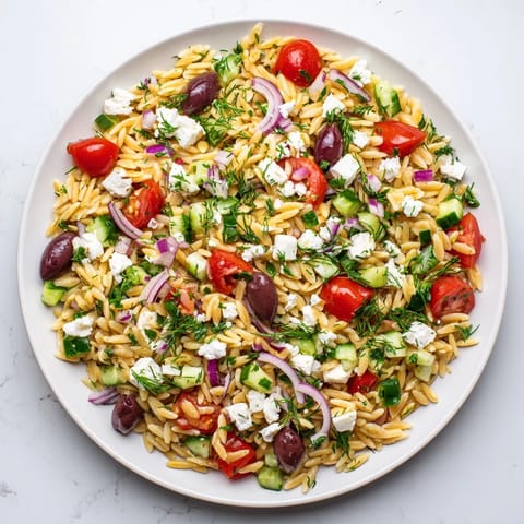 Bright Greek orzo salad with red onion, Kalamata olives, and herbs, served chilled on a rustic wooden board.  