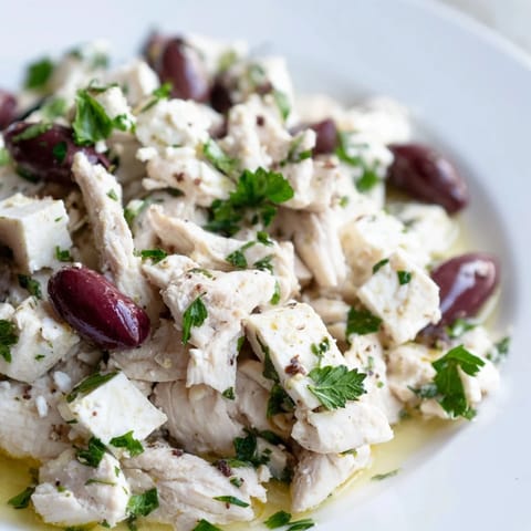 Freshly prepared Mediterranean Chickpea Chicken Salad featuring Kalamata olives, cherry tomatoes, and parsley, served on a light lunch platter.  