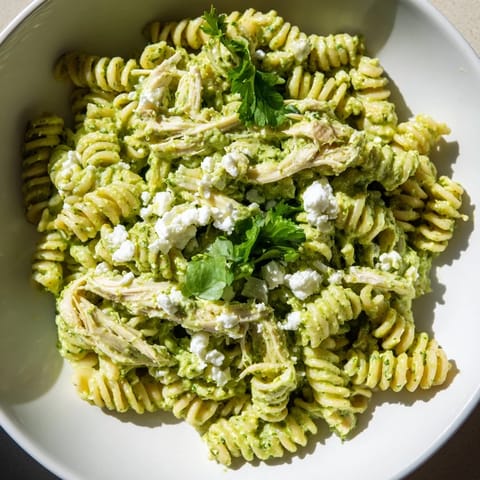 Bright green cilantro lime chicken pasta salad with shredded chicken and lime wedges, perfect for an easy weeknight dinner.