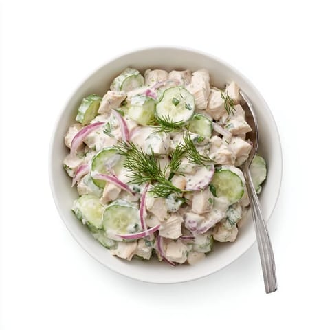 Crisp cucumber slices and tender shredded chicken coated in creamy dill yogurt, served chilled in a white bowl.  
