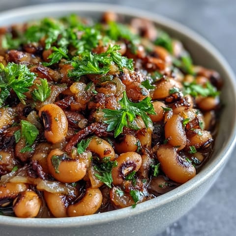 Freshly cooked frozen black-eyed peas simmered in a savory broth with diced tomatoes and herbs, served steaming in a rustic bowl.
