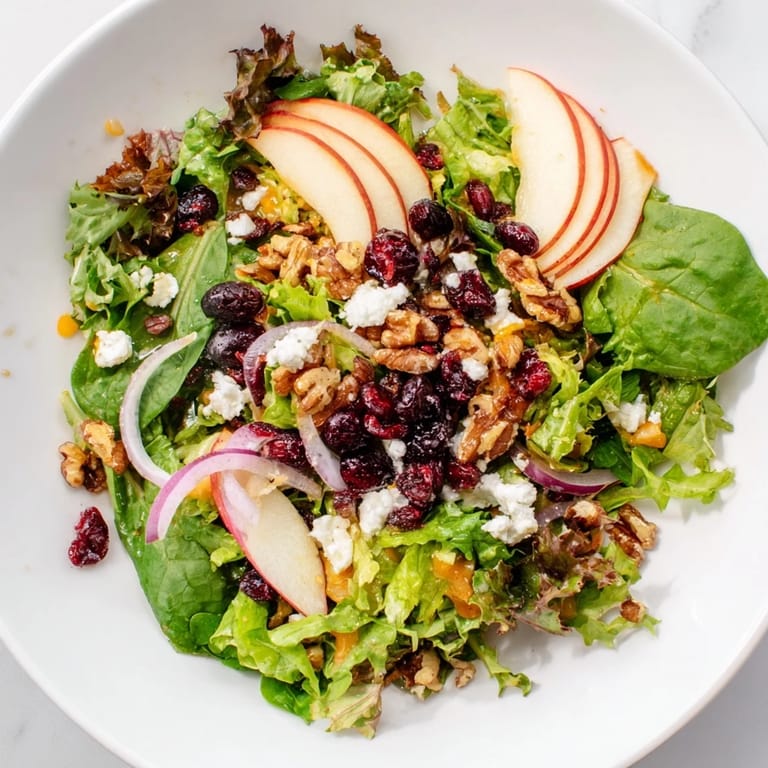 A delicious bowl of Seasonal Cranberry and Walnut Celebration Salad, featuring crisp greens and toasted walnuts.