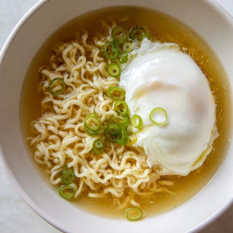 A beautifully plated bowl of upgraded instant ramen, enhanced with butter and a soft egg.