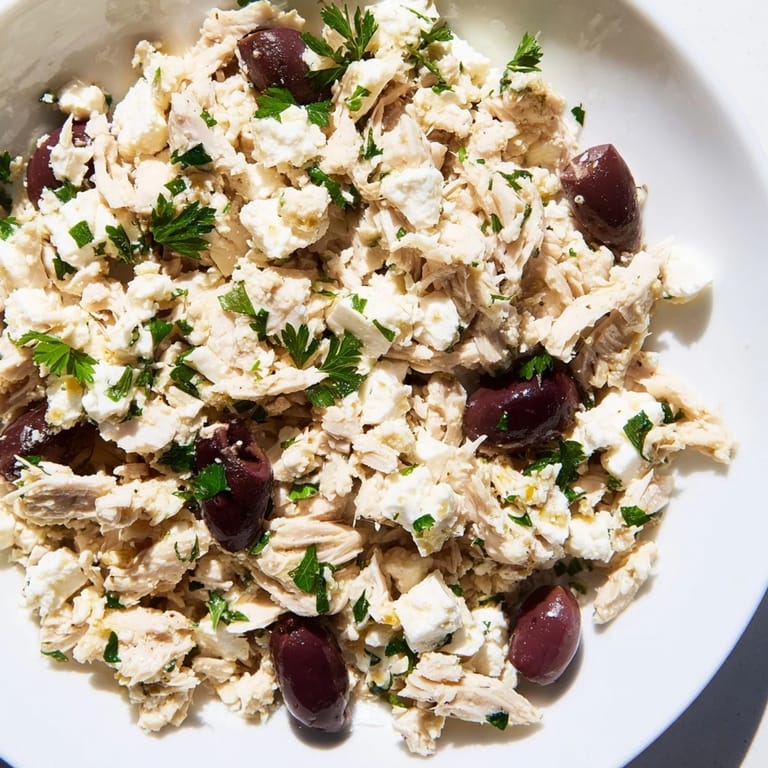 Colorful Mediterranean Chickpea Chicken Salad in a white bowl, drizzled with zesty dressing and garnished with red onion and feta.
