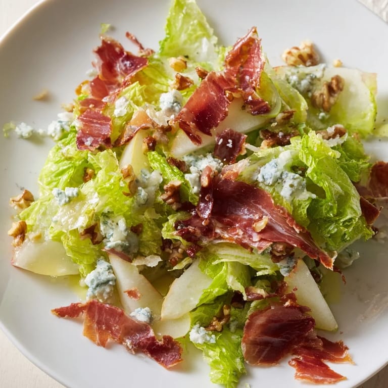 Sliced pears and crumbled blue cheese mingle with frisée and crispy prosciutto on a serving platter.