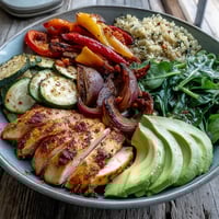 Warm paprika roasted vegetable quinoa bowl with golden chicken, creamy avocado, and lemon salad.